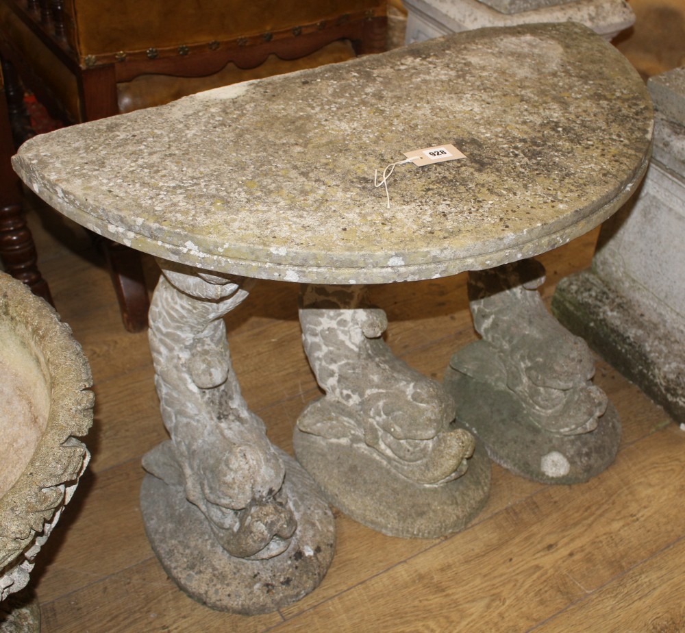 A reconstituted stone demi lune garden seat, on dolphin supports, W.90cm D.45cm H.80cm